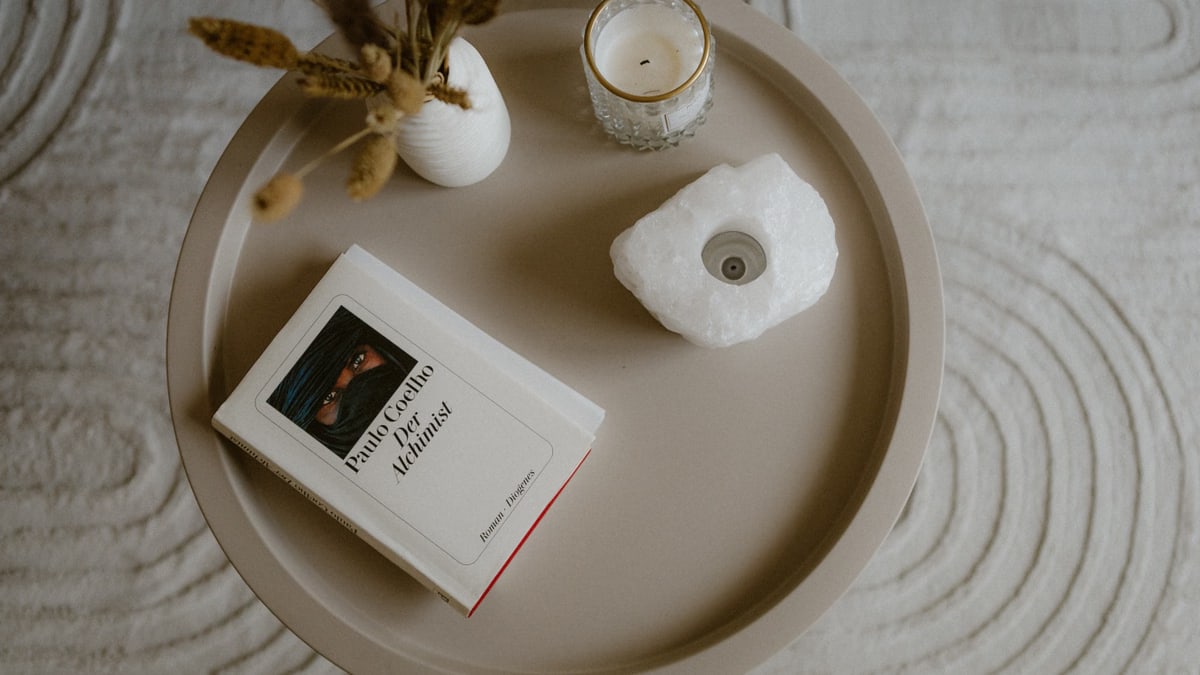 A minimalist tabletop scene featuring a book, a candle, and decor, creating a cozy atmosphere.